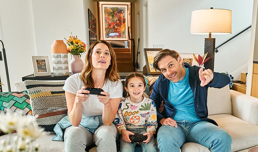 Parents and their young daughter play video games together